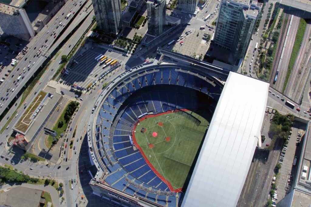 Aerial view of a large, mostly empty baseball stadium surrounded by roads, high-rise buildings, and railway tracks in an urban area.
