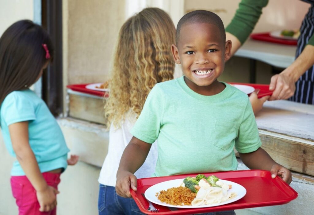 A boy holding a tray of school lunch.